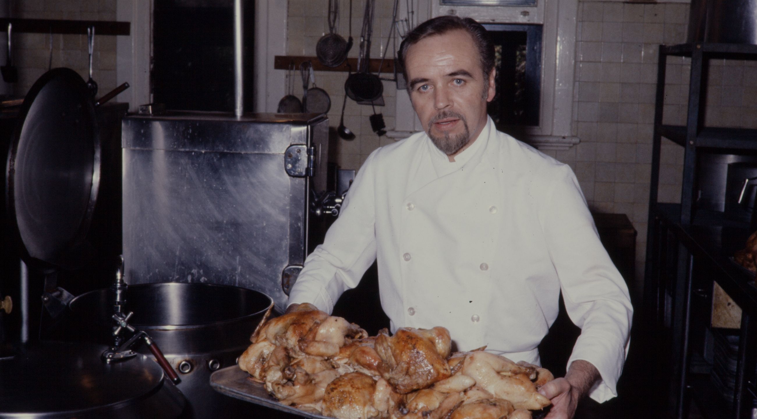 Kitchen staff carrying a tray of cooked chicken