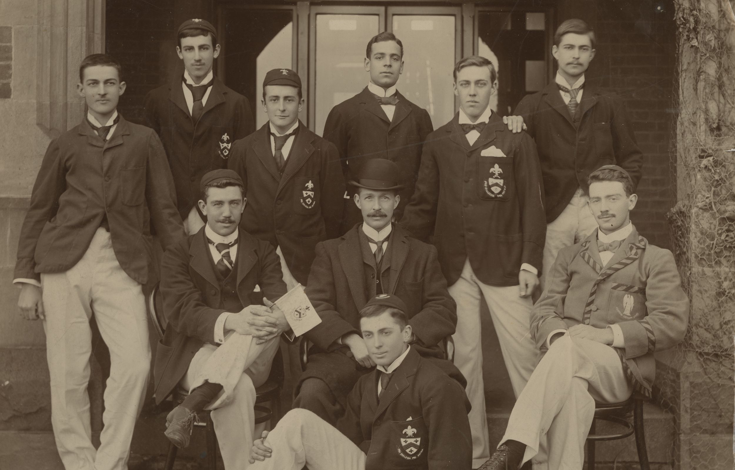 Trinity College rowing crew wearing blazers and caps in front of Clarke Building, 1898.